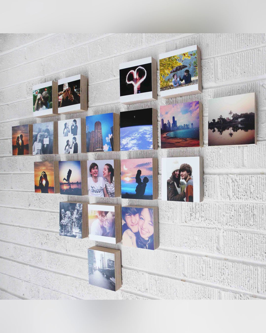 Twenty wood photo blocks arranged in a heart shape on a white painted brick wall