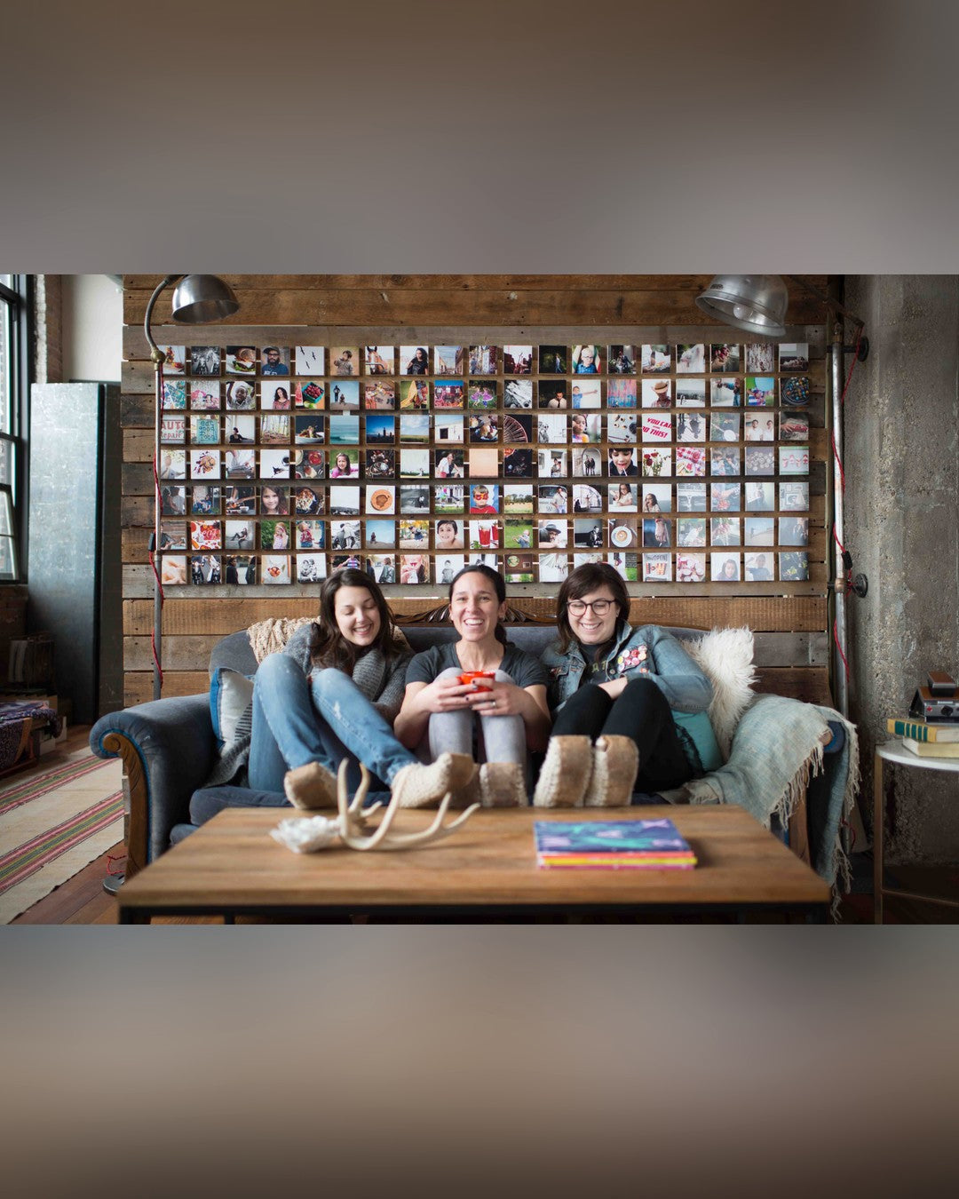 A large wall of small wood photo blocks filling the space above a blue velvet couch