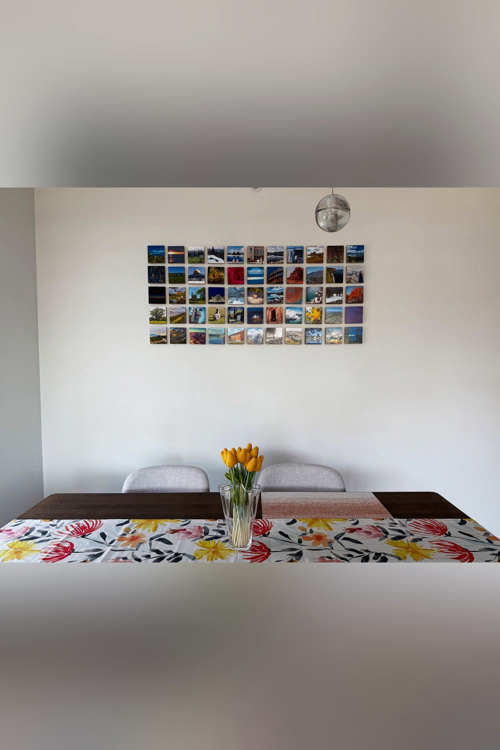 About fifty small wood photo blocks of travel photographs covering a wall above a dining table
