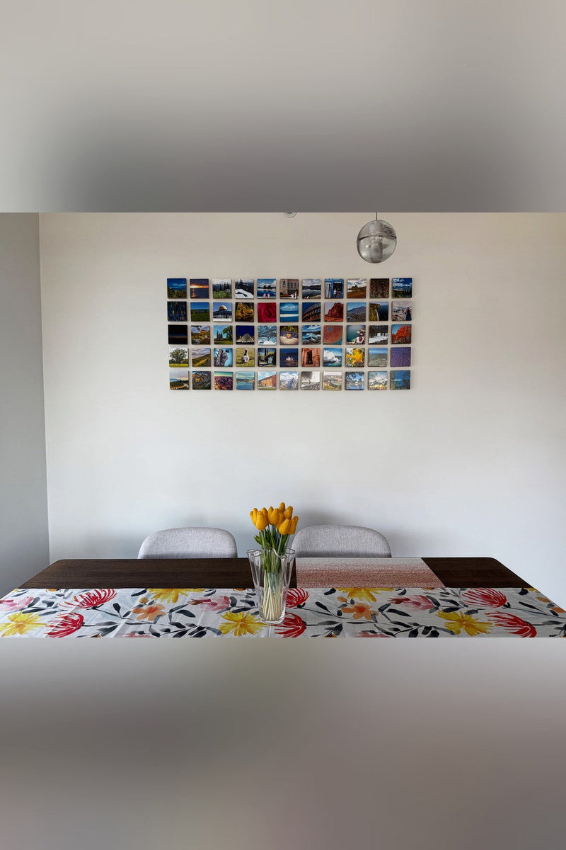 About fifty small wood photo blocks of travel photographs covering a wall above a dining table